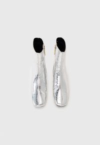 Silberne Knöchelstiefel mit einem glänzenden, metallischen Finish, ausgestattet mit einem Seitenreißverschluss und einem schlanken, spitzen Zehendesign.