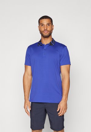 Polo shirt blu royal con colletto nero a motivi, patta con tre bottoni e maniche corte, abbinato a pantaloni corti scuri. Texture liscia.