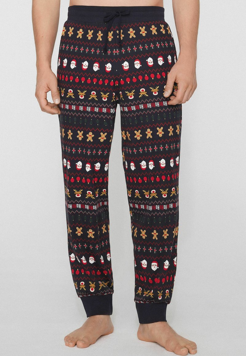 Pantalones de pijama para hombre en azul marino oscuro con un patrón festivo que incluye caras de Santa Claus, muñecos de jengibre y renos en rojo, blanco y dorado. Cintura elástica.