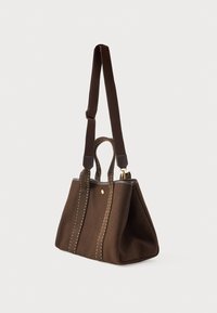 Καφέ υφασμάτινη τσάντα tote με διπλές λαβές και ρυθμιζόμενο λουρί ώμου, με λευκή ραφή και μικρό χρυσό κλείσιμο με κουμπί.