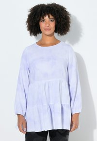 Lichte lavendelblauwe blouse met lange mouwen en een ronde hals, voorzien van een gelaagde look en een gestructureerde, gerimpelde stof. Gecombineerd met een donkere broek.