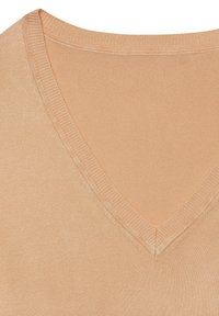 Leicht pfirsichfarbener V-Ausschnitt-Strickoberteil. Weiche Textur mit geripptem Saum am Halsausschnitt und einem glatten Körper.