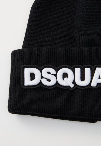 Bonnet en tricot noir avec revers, arborant un logo brodé blanc indiquant "DSQUARED" sur un fond texturé.