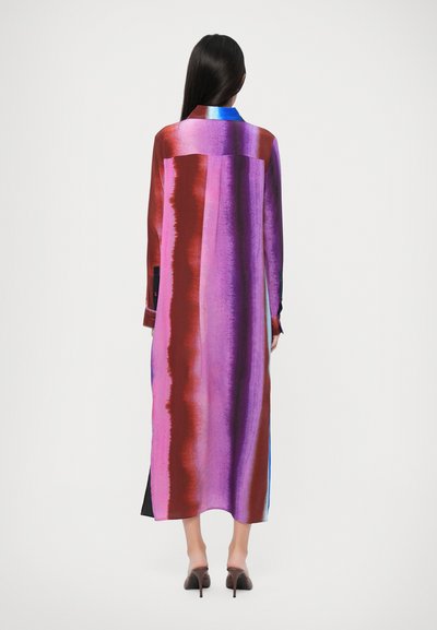 Rochie lungă colorată cu dungi verticale îndrăznețe în nuanțe de violet, roșu și albastru. Construită dintr-un material neted, cu guler și mansete cu nasturi.