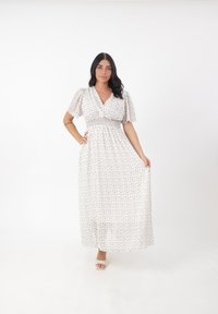 Abito maxi in un leggero tessuto bianco con piccoli motivi floreali in colori pastello. Vita arricciata e maniche a sbuffo corte.