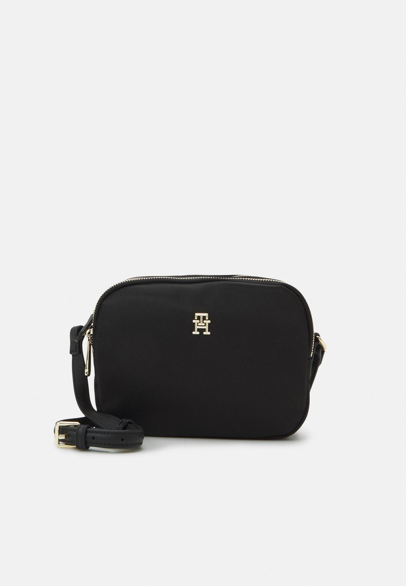 Sort crossbody taske lavet af stof med en glat tekstur, der har et logo i guldfarvet tone, lynlås lukning og justerbar rem.