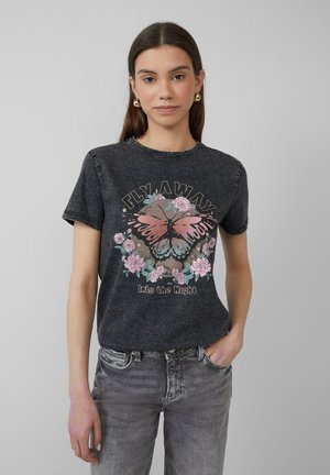 Zwarte katoenen t-shirt met korte mouwen, voorzien van een grafische print van een vlinder en bloemen. Rechte snit met een ronde hals.