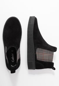 Bottines noires en suède avec une semelle en caoutchouc texturé, présentant un accent textile à motif à carreaux sur les côtés et une ouverture élastique pour un enfilage facile.