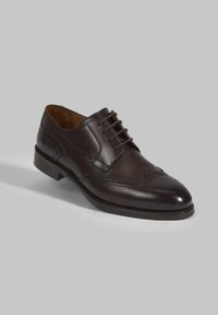 Donkerbruine leren oxford schoen met wingtipdesign, geperforeerde details en een ronde neus. Voorzien van een vetersluiting en een gestapelde hak.