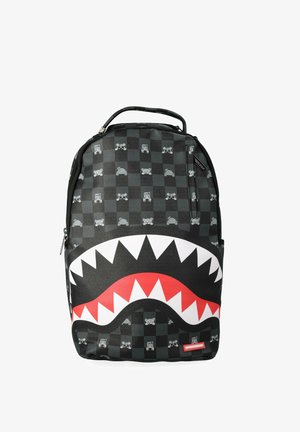 Zaino a quadri nero e grigio con piccole icone e una grande bocca aperta stilizzata con denti bianchi e rossi dentellati sulla parte anteriore.