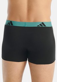 Svarta boxershorts med en teal-färgad midjeband som har tre svarta ränder. Materialet verkar slätt, med en tajt passform och utan synliga mönster.