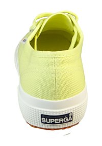 Baskets en toile jaunes avec une tige texturée, semelle blanche et un logo bien visible sur le talon. Présente un design à lacets et un profil bas.