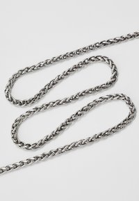 Sølvmetal kjede med en tvistet design og blanke, sammenvevde ledd. Glatt tekstur med jevn tykkelse gjennom hele. 