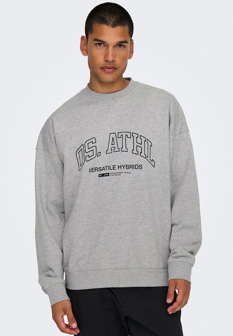 Gray sweatshirt with a crew neck, oversized fit, and black lettering "OS. ATHL VERSATILE HYBRIDS" printed across the chest. Cotton blend material.