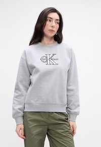 Γκρι φούτερ από μείγμα βα�μβακιού, με στρογγυλή λαιμόκοψη και κεντημένο λογότυπο 'Calvin Klein' σε μαύρο χρώμα. Ριμπά μανίκια και στρίφωμα.