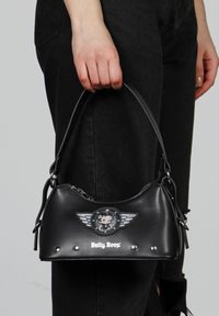 Bolso de mano de imitación cuero negro con forma curva, que presenta un gráfico de Betty Boop, diseño alado y tachuelas plateadas en la parte inferior.