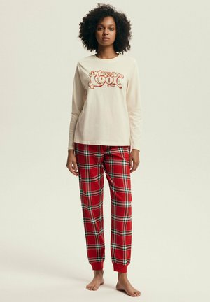Kremowa koszula z długim rękawem z grafiką "stay cool", w połączeniu z czerwonymi spodniami piżamowymi w kratę, z zielonymi i białymi akcentami oraz ściągaczami.