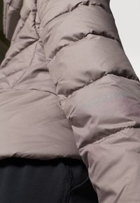 Giacca a vento mauve chiaro con sezioni trapuntate e una superficie liscia. Presenta il marchio ricamato "Didriksons" sulla manica.