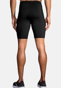 Sorte atletiske shorts med en tæt pasform, lavet af strækbart materiale, med en flad talje og en sidelomme.