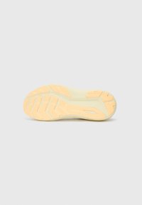 Shoe sole in light yellow rubber, featuring a textured surface with patterned grooves for traction and stability.