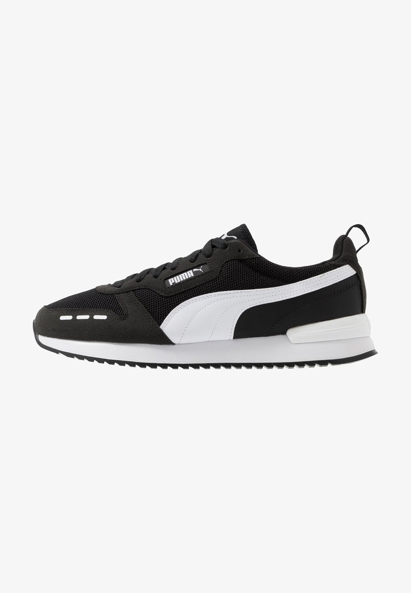 Chaussure de course Puma noire et blanche avec empeigne en mesh, bande blanche Puma, fermeture à lacets et languette au talon.