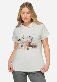 Sudadera corta de manga corta blanca con cordón, que presenta una impresión de collage gráfico en colores suaves. Tejido suave, corte relajado y sutil textura.