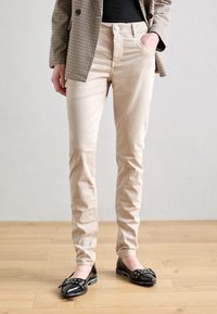 Beige, slim-fit byxor i bomull. Har framfickor, klassisk femfickarsstil och en mjuk textur. Matchar med svarta ballerina.