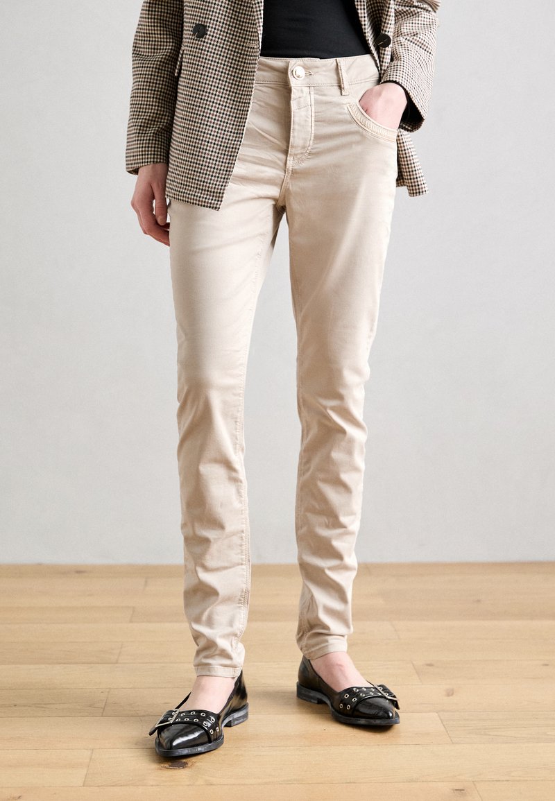 Beige, slim-fit byxor i bomull. Har framfickor, klassisk femfickarsstil och en mjuk textur. Matchar med svarta ballerina.