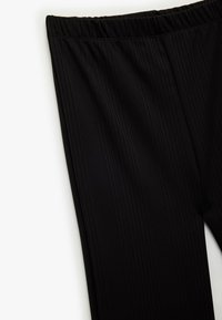 Sorte ribbede leggings med elastisk talje, der har lodrette striber og en glat tekstur. Minimalistisk design uden synlige dekorationer.