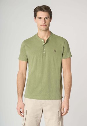 T-shirt verde oliva a maniche corte con colletto henley e bottoni e un sottile dettaglio del logo. Tessuto morbido con una vestibilità comoda e rilassata.