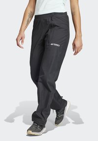 Pantalons d'extérieur légers et noirs avec une bande élastique à la taille, une poche zippée sur le côté et un logo TERREX. Texture lisse, conçus pour une utilisation active.