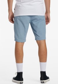 Light blue shorts with a smooth texture, rolled hems, and side pockets, paired with white socks and black high-top sneakers.