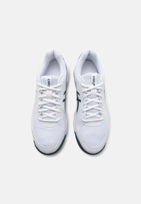 Hvite atletiske sko med mesh-stoff, fremtredende grønn ASICS-logo, rund tå og polstret krage. Snøringer for sikker passform. Gummisåle.