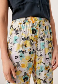 Bloemenpatroon broeken in pastelkleuren met zwarte, gele en teal accenten; voorzien van een elastische tailleband met een trekkoord. Textuurstof.