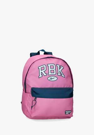 Mochila rosa con bolsillo frontal azul marino, letras "RBK" y logotipo de Reebok sobre fondo blanco.