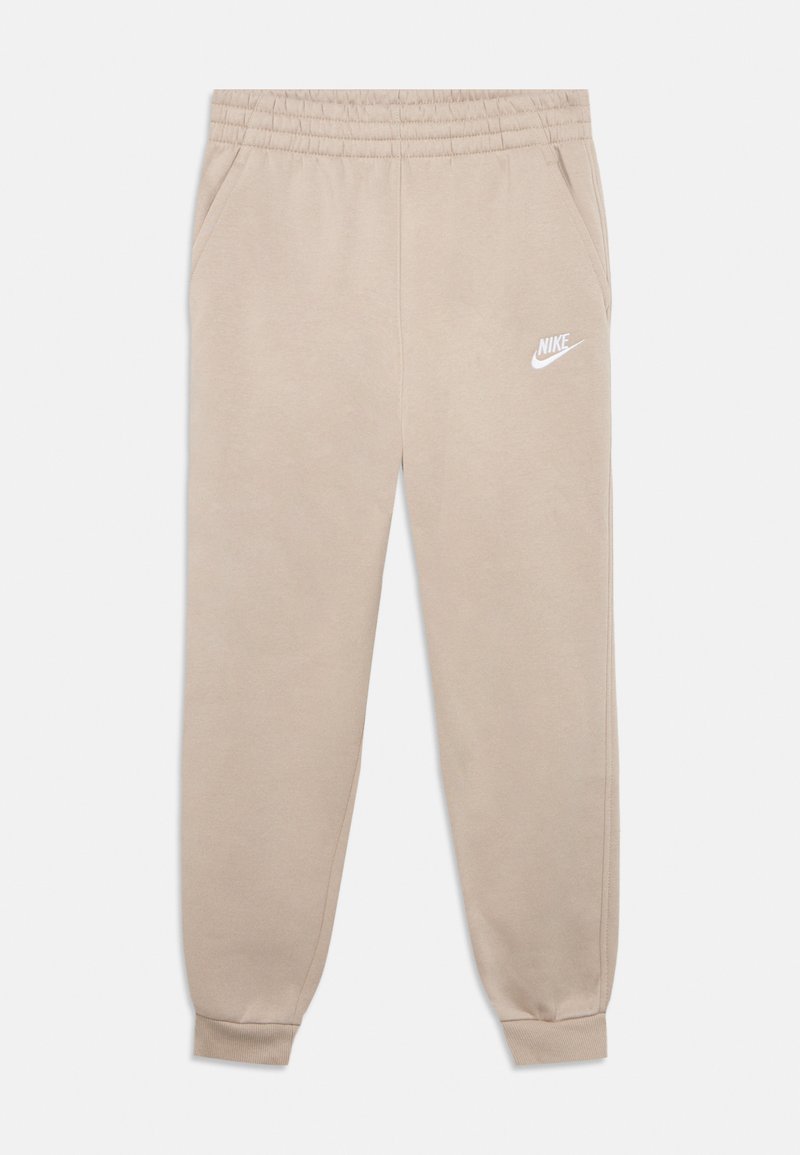 Pantalon de survêtement beige en tissu doux avec une taille élastique, des poches latérales et un logo Nike blanc sur la cuisse gauche.