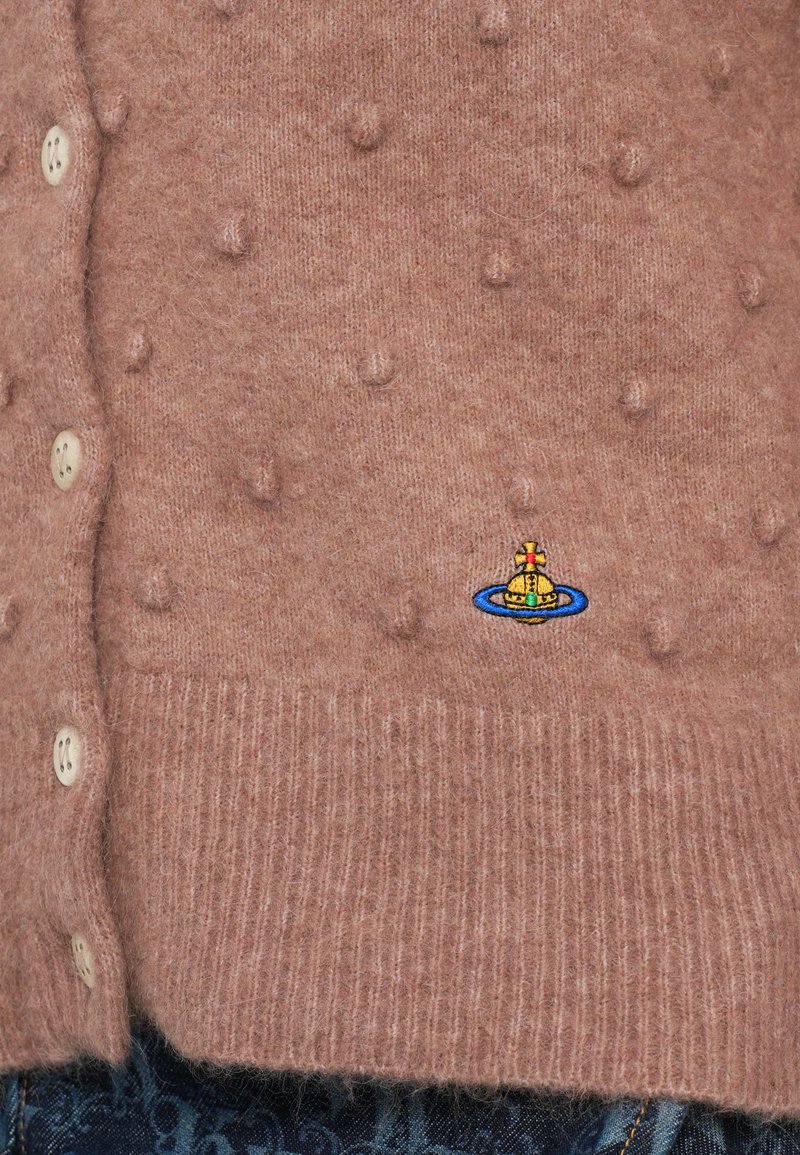 Roze gebreide cardigan met een textuurpatroon van kleine verheven bultjes, een ribgebreide zoom, en een kleurrijk geborduurd bootontwerp nabij de onderrand.