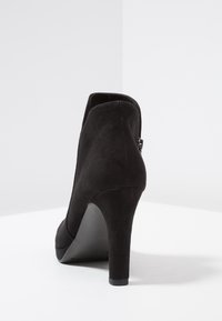 Schwarze Wildleder-Stiefelette mit hohen Absätzen, runder Spitze, glatter Textur und einem Reißverschluss auf der Rückseite.