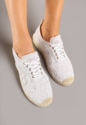 Chaussures blanches à lacets en crochet, présentant des motifs floraux complexes et une cap de toe tissée en jute naturelle.