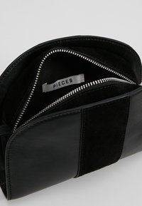 Clutch bag in pelle nera e suede con chiusura a zip, caratterizzata da una finitura liscia, tasca interna con zip e etichetta del marchio.
