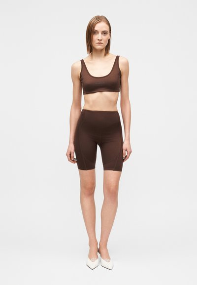 Conjunto deportivo marrón compuesto por sujetador y pantalones cortos de ciclismo con una textura suave, que presenta un escote redondo y detalles de costuras sutiles. Acentuado con la palabra "SILENCE."
