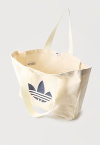 Τσάντα ώμου σε κρεμ χρώμα με μακριές λαβές και μεγάλο μαύρο λογότυπο Adidas στο μπροστινό μέρος, εμφανιζόμενη ανοιχτή και άδεια.