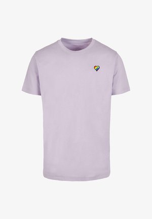 Heled lavendliturusest puuvillane T-särk lühikeste varrukatega, ümar kaelus ja väike vikerkaare südame graafika vasakul rinnal. Pehme tekstuur.