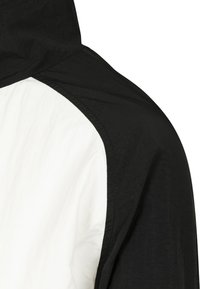 Chaqueta con capucha que presenta una combinación de colores en blanco y negro. Tejido texturizado con paneles contrastantes, que exhibe un diseño moderno y un corte ajustado.
