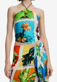 Top halter e gonna avvolgente in un vivace tessuto a fantasia floreale. Presenta stampe multicolori con etichette testuali, una texture morbida e una chiusura a legaccio.