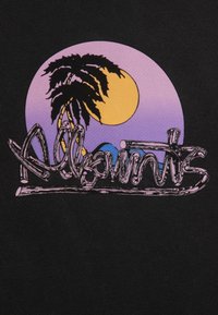 Svart tyg har en grafisk design med en lila solnedgång, en silhuett av en palm och stiliserad text i en svängd stil.