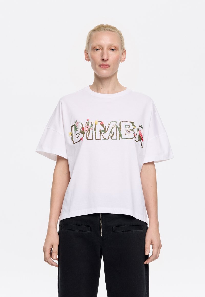 Witte katoenen t-shirt met een oversized pasvorm, voorzien van bloemmotieven die het woord "BIMBA" op de voorkant vormen. Korte mouwen en een ronde hals.