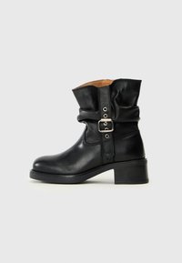 Botte de cheville en cuir noir avec un design froncé, présentant un détail de boucle sur le côté et un talon bloc bas. Texture lisse et bout rond.