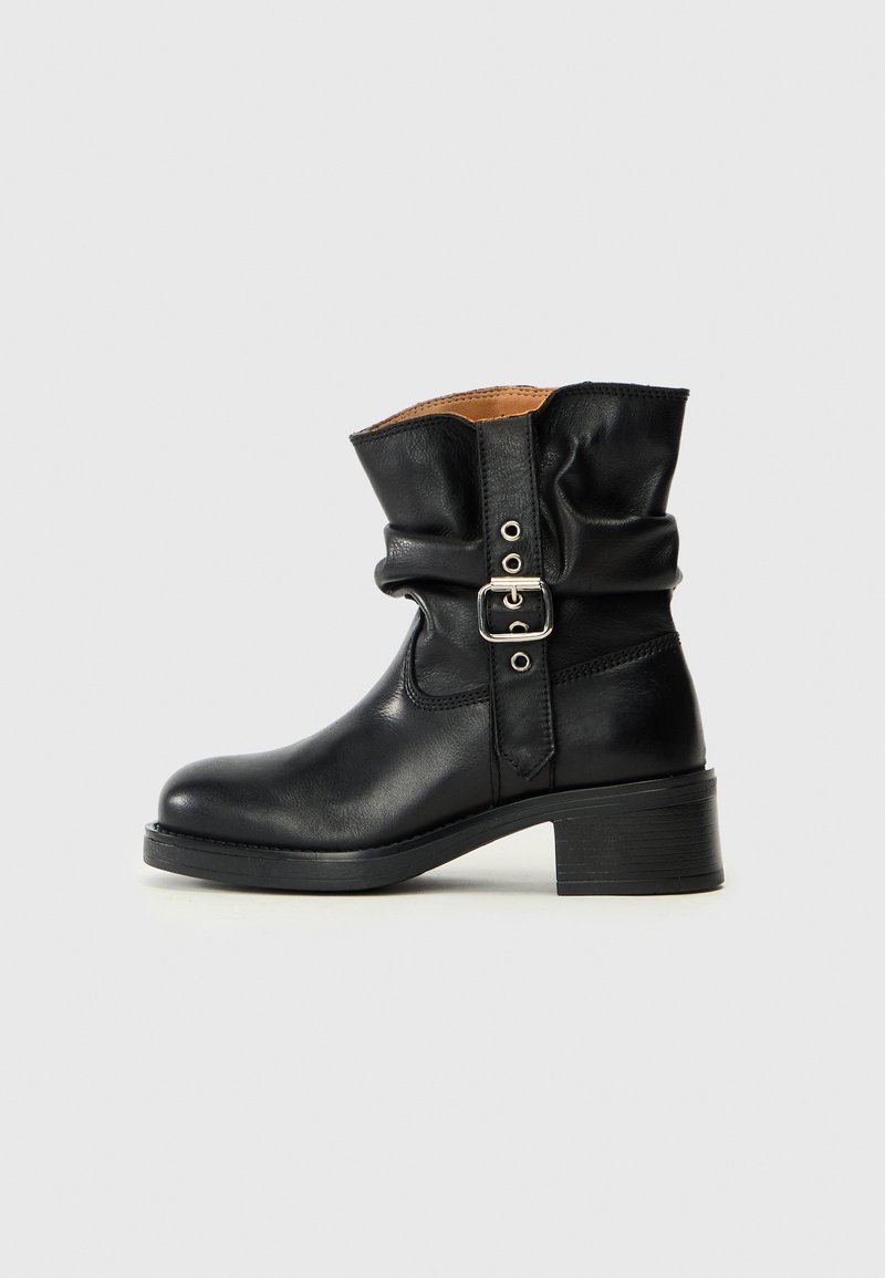 Botte de cheville en cuir noir avec un design froncé, présentant un détail de boucle sur le côté et un talon bloc bas. Texture lisse et bout rond.