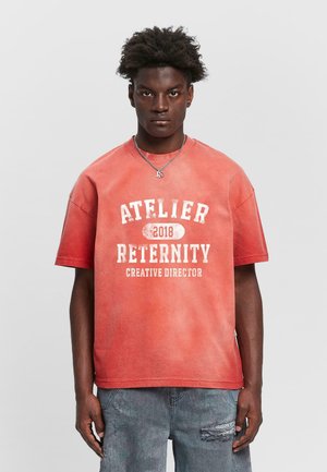 Red cotton t-shirt with a crew neck, featuring white text "ATELIER RETERNITY 2018 CREATIVE DIRECTOR" in a distressed font. Casual fit.